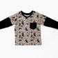 A toddler's long-sleeve shirt with black sleeves and a beige patterned body featuring cartoon ghosts, skulls, and red roses, laid flat on a white background.