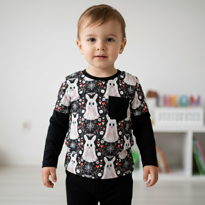 Child wearing a black long-sleeve shirt with white bunny patterns in a room.