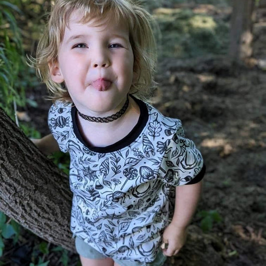 Goth kid wearing a handmade tshirt, white with spooky black designs