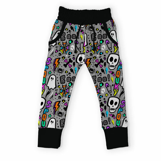 Gray kids' jogger pants with a colorful Halloween pattern of skulls, ghosts, and lightning bolts, featuring black ribbed cuffs and waistband.