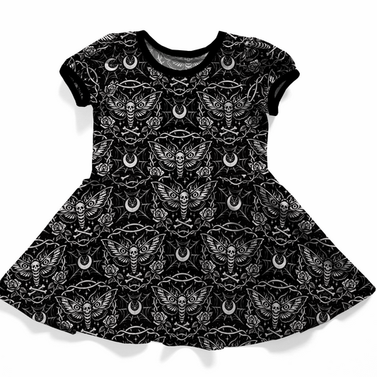 Goh baby, toddler or youth dress, short sleeves, black with white pattern. 
The print features dead head moth, moons, spiderwebs, roses and bones. 